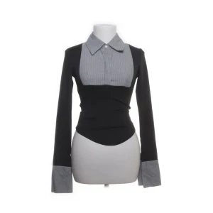 Svart och grå långärmad topp med krage - Snygg svart långärmad topp med grå- och vitrandiga detaljer på krage, bröst och ärmslut. Figurnära passform och markerad midja.