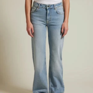 Ljusblå jeans med hög midja - Snygga ljusblå jeans med hög midja och en avslappnad wide fit. Perfekta för en trendig look, dessa jeans har en klassisk femficksdesign och stängs med dragkedja och knapp. De är tillverkade i ett bekvämt denimtyg som ger en skön känsla hela dagen.