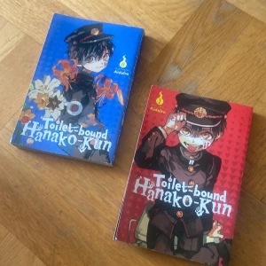 Toilet-bound Hanako-Kun Volym 1 & 2 - Säljer två manga-volymer av 'Toilet-bound Hanako-Kun' av AidaIro. Omslagen är färgstarka, volym 1 i rött och volym 0 i blått, båda med detaljerade illustrationer av huvudkaraktären i skoluniform och blommor. Perfekt för mangaälskare och samlare! Ordinarie 190 kr var