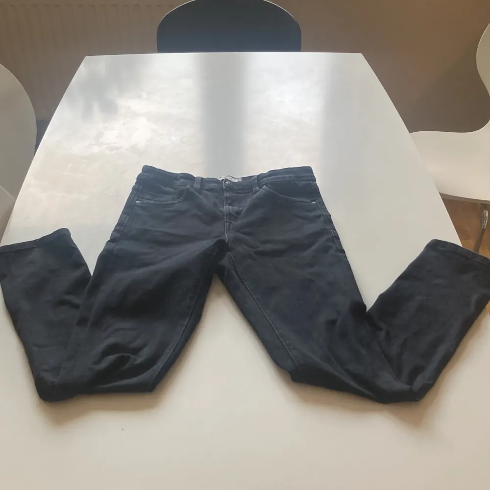 Säljer ett par svarta jeansbyxor från Name It i storlek 164. Klassisk femficksmodell med knapp och dragkedja framtill. Byxorna har en rak passform och är perfekta för dig som gillar en enkel och stilren look.. Farkut & Housut.