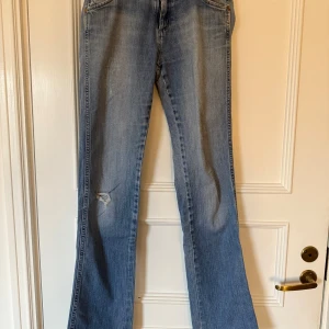 Lowwaist bootcut jeans från Wrangler - Säljer ett par klassiska blå bootcut jeans från Wrangler. Låg till normal midja. Superskönt material. Köpta i Paris! Mått: 99cm ytterbenslängd, 39cm midjebredd