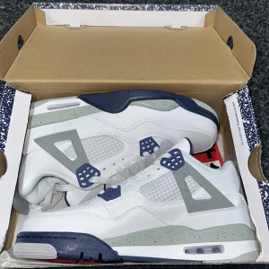 Nike Air Jordans 4 Midnight Navy  - Säljer ett par Nike Air Jordans 4 i färgen White Oreo. Skorna har en vit ovandel i skinn med grå och mörkblå detaljer samt röda accenter under sulan. Klassisk meshpanel på sidorna och synlig Air-enhet i sulan. Kommer med originalkartong.
