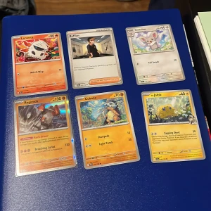 Pokémonkort - 6 st blandade - Säljer ett set med 6 Pokémonkort: Larvesta, Ruffian (Trainer), Cinccino, Regirock (holo), Cubone och Joltik. Färgglada motiv och klassisk Pokémon-design. Perfekt för samlare eller spelare som vill utöka sin samling.