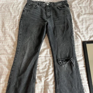 Svarta bootcut jeans med slitning - Säljer ett par svarta lågmidjade bootcut jeans med slitning på ena benet. Pris kan diskuteras vid snabb affär. 