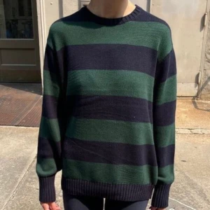  Brandy Melville brianna sweater - Säljer en stickad tröja från Brandy Melville med breda mörkgröna och marinblå ränder. Tröjan har lång ärm och ribbade muddar vid ärmslut och nederkant. Perfekt för en avslappnad och trendig look.