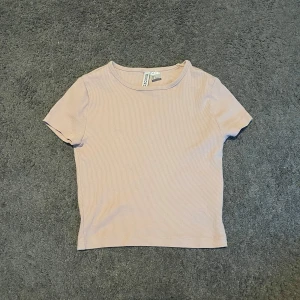  t-shirt från H&M Divided - Säljer en t-shirt från H&M Divided. T-shirten har korta ärmar och en klassisk rund halsringning. Perfekt basplagg att matcha med allt i garderoben! Står att det är storlek s men den passar på mig som har xs