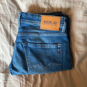 Blå jeans från Replay - Blå jeans från Replay med klassisk femficksdesign och en lätt tvättad look. Märkeslappen i läder sitter på baksidan av midjan.