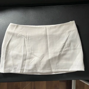 Lågmidjad vit kjol - Säljer en söt lågmidjad vit kjol med inbyggda shorts ifrån shein, aldrig använd då den inte passa mig💕