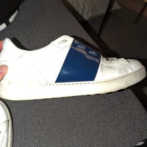 Valentino open  - Säljer ett par vita sneakers från Valentino Garavani med blåa detaljer. Perfekta för sommaren. De är i hyfsat skick men ser ändå att de är använda. Ända är att original innersulorna är sönder. Men skickar me några som passar ändå.  Har dustbag. Dessa går för ca 6-7 mitt pris 1000