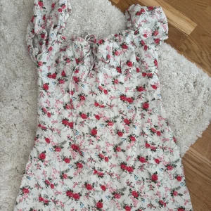 Blommig klänning från Shein - Säljer en söt blommig klänning från Shein i storlek S. Klänningen har korta ärmar och ett fint snörningsdetalj baktill. Perfekt för sommarens alla tillfällen! 🌸🩷🤩