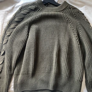 Grön stickad tröja  - Grön stickad tröja med snygga detaljer längst armarna 