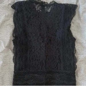 Svart spetsblus - Elegant svart spetsblus med broderingar och öppen rygg