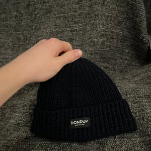 Marinblå mössa från Dondup - Säljer en marinblå mössa från Dondup med uppvikt kant och logotyp framtill. Perfekt för kyliga dagar och enkel att matcha med olika outfits. 