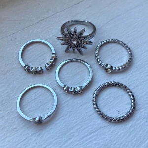  Silverfärgade ringar - Säljer ett set med 6 ringar i silverfärg. Dom har snygga detaljer som små stenar och är aldrig använda! 