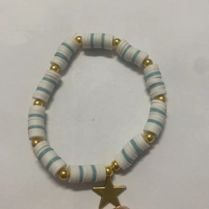 Vita och turkosa armband med gulddetaljer - Säljer tre stilrena armband med vita och turkosa pärlor samt guldfärgade detaljer. Varje armband har en unik berlock: en stjärna, ett löv och texten 'LOVE'. Perfekta för att ge en personlig touch till din stil.