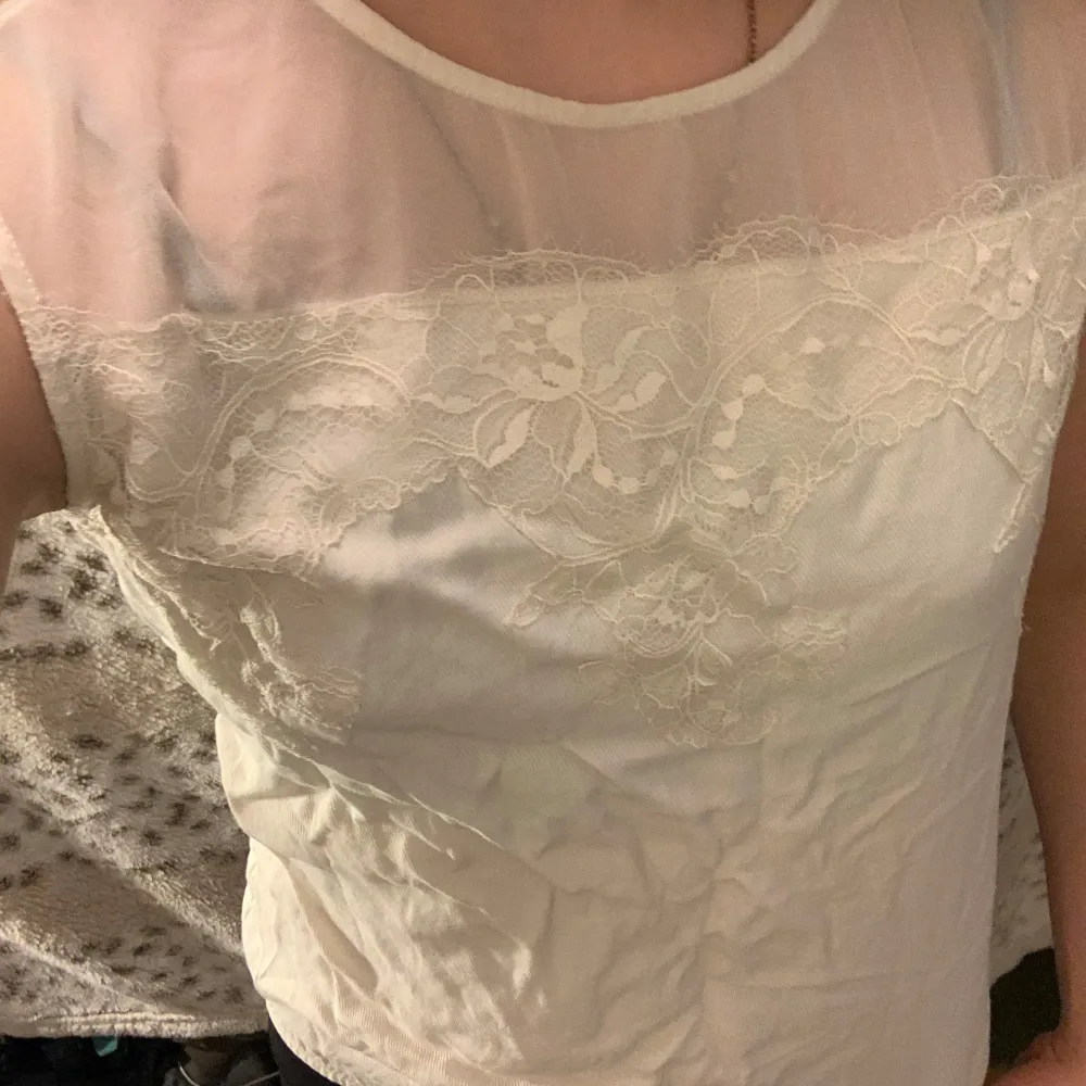Säljer en elegant vit topp från Massimo Dutti med vackra spetsdetaljer över bröstet. Toppen är ärmlös och har en rund halsringning. Perfekt för en stilren look.( pris kan diskuteras!). Yläosat.