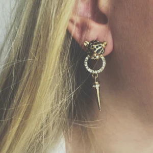 Guldörhängen med leoparddesign (BARA EN) - Snygga guldörhängen med leopardhuvud och en glittrig ring som hänger ner till en spetsig detalj. Perfekta för att ge en djärv touch till din stil.