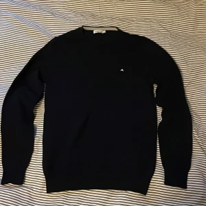 Mörkblå tröja från J.Lindeberg - Säljer en stilren mörkblå tröja från J.Lindeberg. Utmärkt skick förutom ett lagat hål (bild två) som dock inte syns vid användning, finns en liten slitning vid nacken också, men inget man tänker på. Storlek M men passar säker S också. 100% merino. Pris går att diskutera vid snabb affär