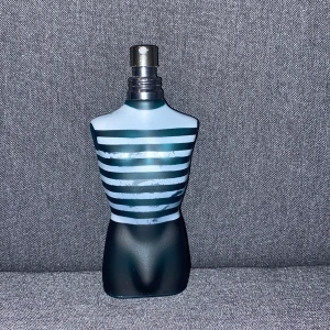Le Male Parfym från Jean Paul Gaultier - Ikonisk parfymflaska formad som en manlig torso med blå och vita ränder. Flaskan står på en röd bas och kommer med en metallisk förpackning. En klassisk doft som är både fräsch och maskulin. 75 ml flaska men det är cirka 30 ml kvar. Säljer parfymen då jag har andra parfymer och jag behöver pengar 