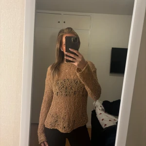 Beige stickad tröja - Säljer en beige stickad tröja med långärmad design. Tröjan har en unik textur och en lös passform som ger en avslappnad look. Perfekt för kyligare dagar.