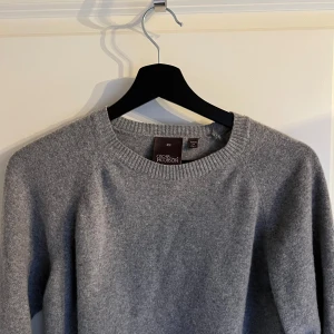 Grå tröja från Oscar Jacobson - Säljer en stilren grå tröja från Oscar Jacobson, tillverkad i Italien. Tröjan har en klassisk design med rund hals och långa ärmar, perfekt för en elegant och avslappnad look.