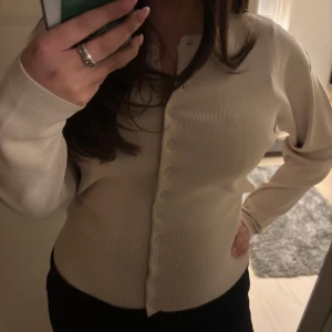 Beige kofta från Zara - Säljer en stilren beige kofta från Zara. Den har långa ärmar och knappar framtill. Perfekt för en elegant och avslappnad look. Använd fåtal gånger. 