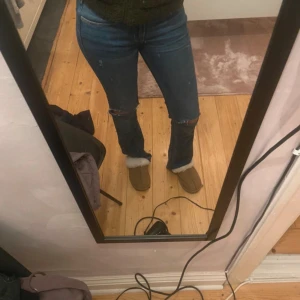 Blå jeans med slitningar - Snygga blå jeans med slitningar vid knäna. De har en tight passform och är perfekta för en avslappnad stil. Jeansen har en klassisk design med fem fickor och knappgylf.