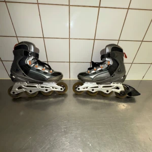 Inlines från Revolution Pro Speed XT - Säljer ett par grå och svarta inlines från Revolution Pro Speed XT. De har orange detaljer och snörning för bra passform. Perfekta för en tur i parken eller längs strandpromenaden.