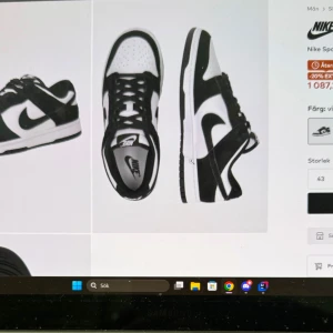 Nike Dunk i svart och vit - Snygga Nike Dunk sneakers i klassisk svart och vit färgkombination. Skorna har en stilren design med snörning och den ikoniska Nike-loggan på sidan. Perfekta för en sportig och trendig look.