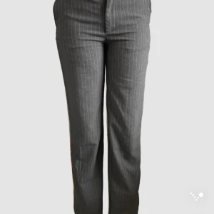 Grå randiga kostymbyxor - Snygga grå kostymbyxor med diskreta vita ränder. Byxorna har en klassisk straight passform och är perfekta för en stilren look. De är tillverkade i ett bekvämt material som ger en elegant känsla.