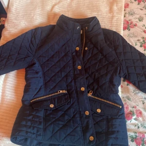 Mörkblå quiltad jacka från Zara - Säljer en snygg mörkblå quiltad jacka från Zara. Jackan har en stilren design med dragkedja och knappar framtill samt praktiska fickor med dragkedjor.