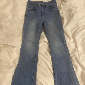 Blå bootcut jeans - Snygga blå bootcut jeans med klassisk femficksdesign. Perfekta för en avslappnad stil med en touch av retro. De har en bekväm passform och är tillverkade i ett mjukt denimtyg.