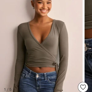 Olivgrön omlottopp - Snygg olivgrön omlottopp med lång ärm och knytning i midjan. Perfekt för en stilren look. Storlek XS och aldrig använd! 