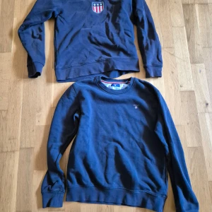 Mörkblå tröjor med emblem - Två mörkblå tröjor, en med ett emblem på bröstet. Perfekta för en avslappnad stil. Tröjorna har långa ärmar och rund halsringning.200kr för båda eller en 100kr stycken. 