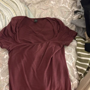 Vinröd topp med djup urringning Shein - En vinröd topp från Shein med korta ärmar och djup, rund urringning. Enkel och stilren design som passar perfekt till jeans eller kjol. Mjuk och skön bomullskänsla, perfekt för dig som gillar basic men ändå vill sticka ut med färg.