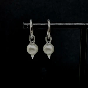 Silvriga örhängen med pärlor och spikes - Coola örhängen i silverfärg med rund pärla och liten spetsig detalj under. Perfekt för dig som gillar att mixa klassiskt med edgy stil. Hängande modell som ger en snygg touch till din look.