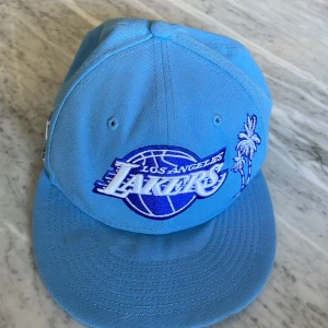 Blå Los Angeles Lakers keps New Era - Säljer nu en LA Lakers keps New Era. Köpt i La förra året för 50 dollar (ca 500kr). Bra skick förutom en liten fläck ( se bild 4). Perfekt till att styla en bra outfit. Storlek: 7 1/4- 57.7 cm               Pris ej hugget i sten   
