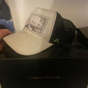 Vit och svart keps Maggiore Limited - Snygg keps från Maggiore i limited edition med vit front och svart mesh baktill. Framsidan har ett broderat motiv och logga, samt böjd skärm. Perfekt för dig som vill sticka ut med en unik accessoar.