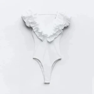 Vit volangbody med djup v-ringning - Supersnygg vit body med djup v-ringning och stora volanger över axlarna. Kroppsnära passform och ärmlös design, perfekt för att skapa en statement-look. Tillverkad i mjukt material som känns skönt mot huden. Säljs inte längre 💕