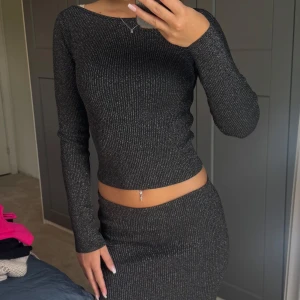 Glittrigt set  - Säljer ett set med en långärmad tröja och långkjol med glittriga detaljer. Kjolen är ribbad och har en tight passform som framhäver figuren. Materialet är stretchigt och skimrar snyggt i ljuset. (Går även att köpa bara kjol/tröja) 