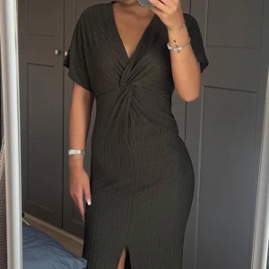 Olivgrön omlottklänning med slits - Säljer en olivgrön långklänning med snygg omlott och v-ringad hals. Figurnära passform och superbekväm att bära. 