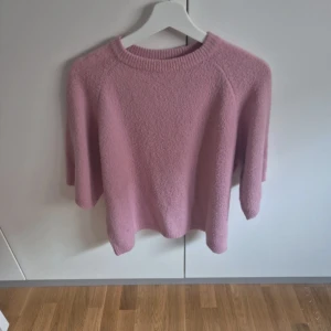 Ljusrosa stickad tröja med trekvartsärm - Säljer en supermysig ljusrosa stickad tröja med rund hals och trekvartsärmar. Perfekt för dig som gillar en chill och avslappnad stil. Tröjan har en loose passform och är gjord i ett mjukt stickat material som känns skönt mot huden.