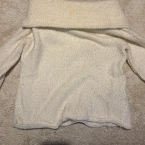 Vit stickad off shoulder tröja  - Säljer en vit stickad. Tröjan har långärmade och är gjord i mjukt material som känns skönt mot huden. Perfekt för att hålla sig varm och ändå se chill ut. Passar dig som gillar enkel och clean stil.