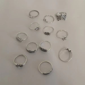 12-pack ringar  - 12 st silverfärgade ringar med olika former och mönster.  Materialet är zinc alloy. (297)