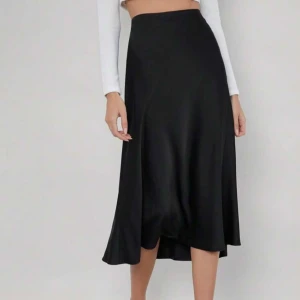 Svart satinkjol från SHEIN XS - Snygg svart midikjol från SHEIN i storlek XS. Kjolen har en mjuk, flowy siluett med lätt glans och är tillverkad i ett syntetmaterial som liknar satin tyg.