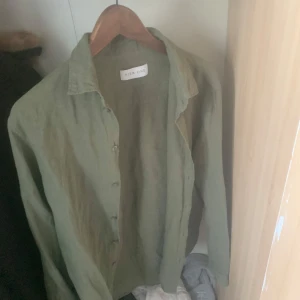 Grön linneskjorta från Pier One - Snygg grön skjorta från Pier One i luftigt linne. Skjortan har klassisk krage, knäppning framtill och långa ärmar. Perfekt för dig som gillar en avslappnad men stilren look.