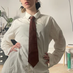 Vintage slips i brunt läder - Brun vintage slips i äkta läder, troligtvis 1980-tal 🫶🏻 superfin för en edgy men uppklädd look ❤️fint och mjukt läder av bra kvalitet