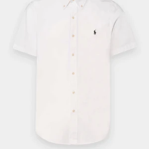 Vit linneskjorta Polo Ralph Lauren S - Fräsch vit kortärmad skjorta från Polo Ralph Lauren i luftig linne. Klassisk button-down med knappar framtill och broderad logga på bröstet. Perfekt till sommarens alla tillfällen, enkel att matcha och riktigt snygg passform.