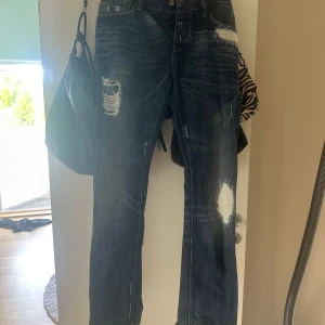 Mörkblå slitna jeans med raka ben - Säljer ett par mörkblå jeans med slitningar och hål på flera ställen. Jeansen har raka ben och klassisk femficksdesign. Super sköna!!💕💕