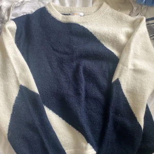 Blåvit stickad tröja Gina Tricot - Säljer en snygg stickad tröja från Gina Tricot i storlek 158/164. Tröjan har ett coolt geometriskt mönster i mörkblått och vitt, rund hals och långa ärmar. Perfekt för dig som gillar stilrena färger och mjuka material.